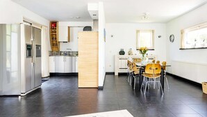 Eine moderne Küche mit Kühlschrank, Schränken und einem Essbereich mit Stühlen und Tisch.