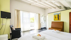 Ein Hotelzimmer mit Bett, Sessel, Fernseher, Bad und Fenster.