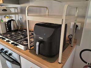 Una cucina con un piano cottura a gas, una moka e un mobiletto portaoggetti bianco.