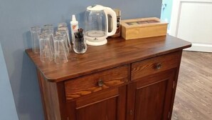A wooden cabinet with glassware and a coffee maker on top.