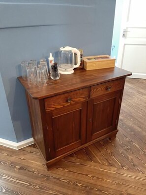 A wooden cabinet with glassware and a coffee maker on top.