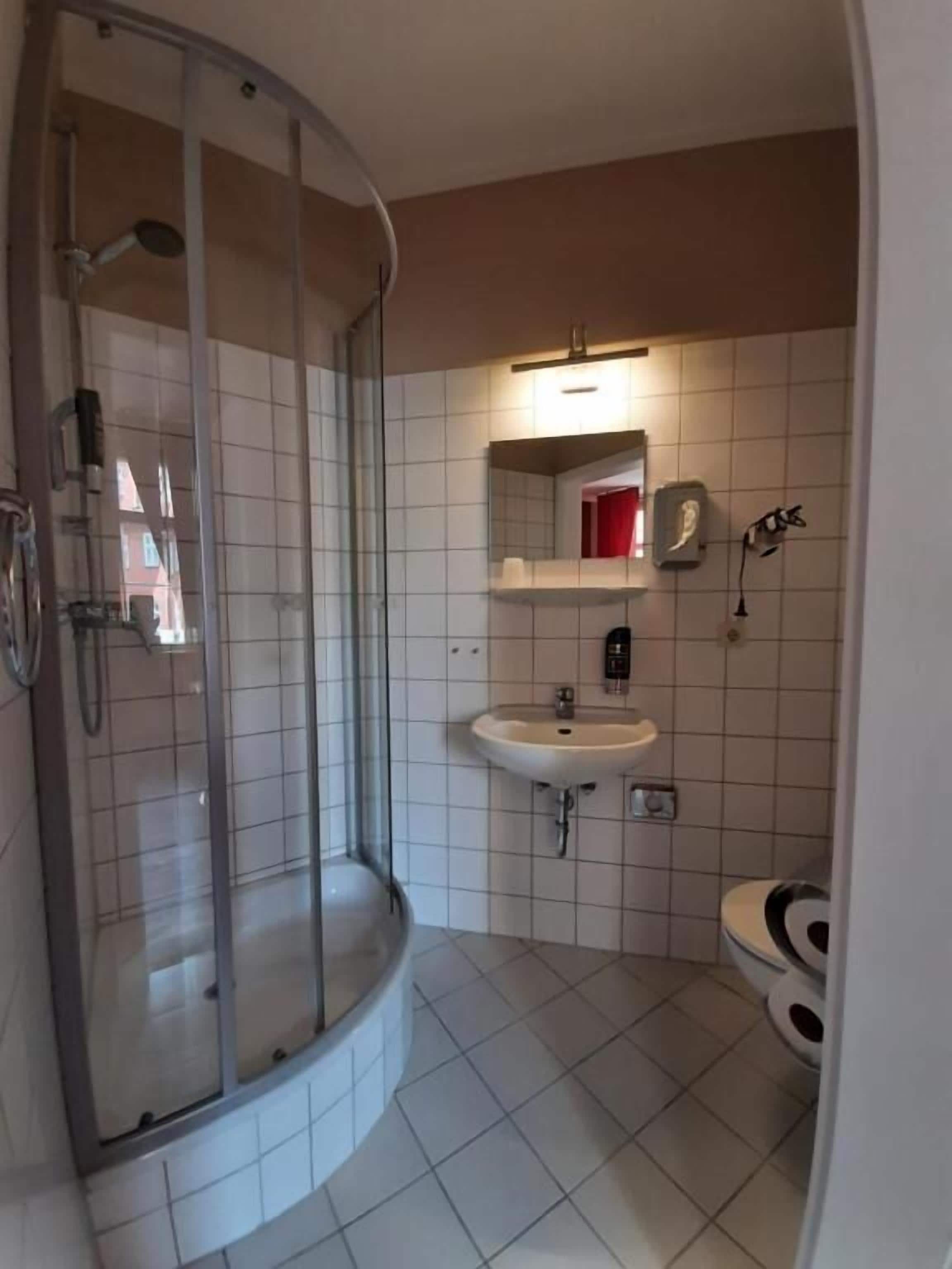 Ein Badezimmer mit einer Dusche in Glasabtrennung, einem Waschbecken und einer Toilette.
