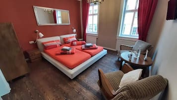 Una camera da letto con un letto, una sedia, un tavolo, uno specchio e una finestra.