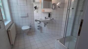 Un baño con inodoro, lavabo y cabina de ducha de vidrio.