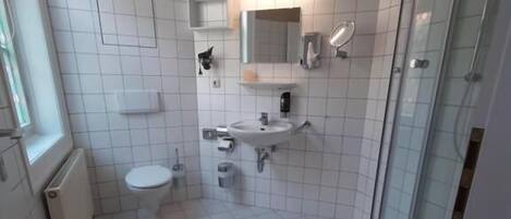 A bathroom with a toilet, sink, and glass shower enclosure.