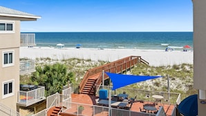 Ein Balkon mit Blick auf den Strand, eine Holztreppe und Gartenmöbel.