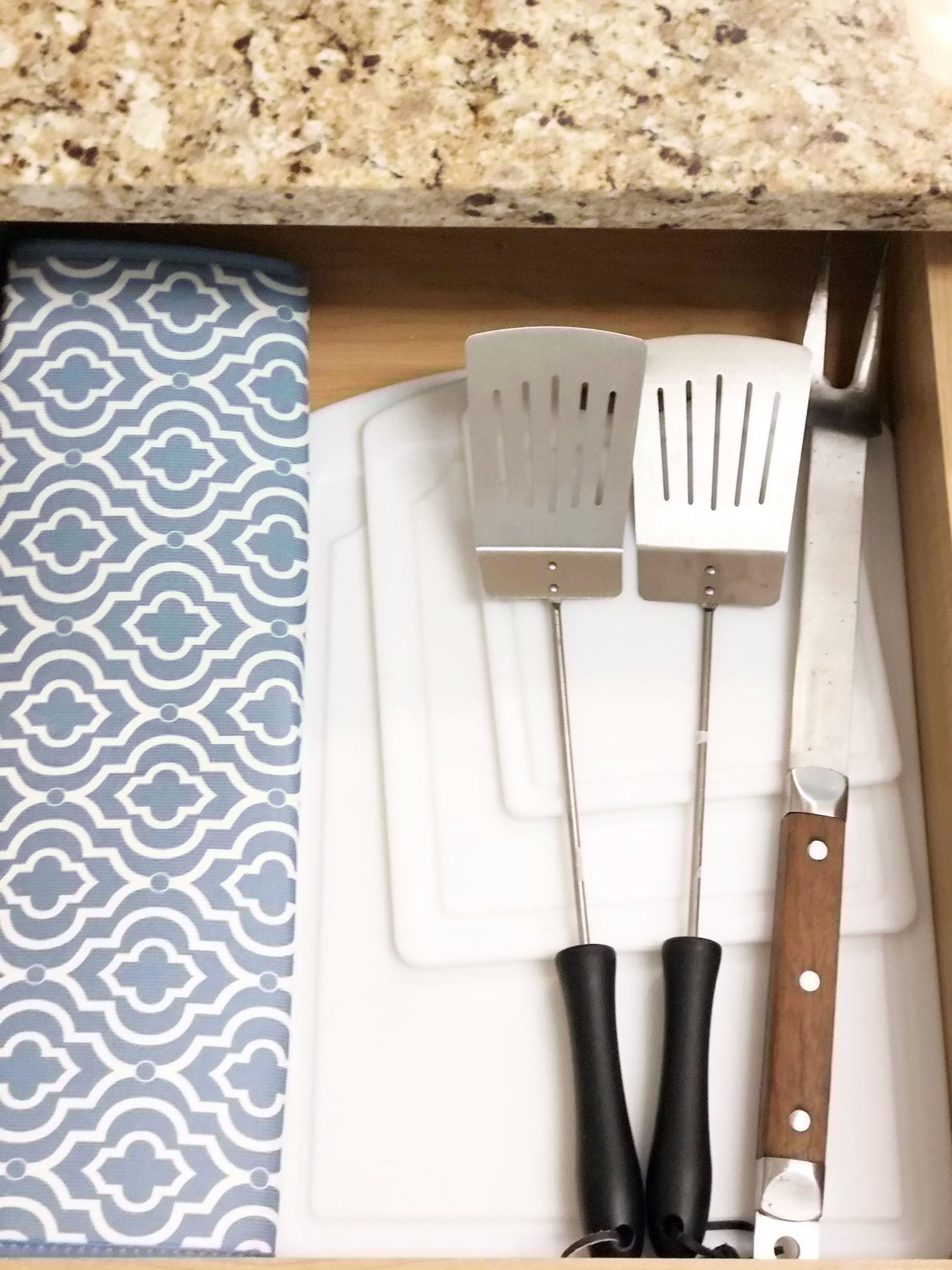 A drawer with two kitchen utensils: two spatulas and a knife.