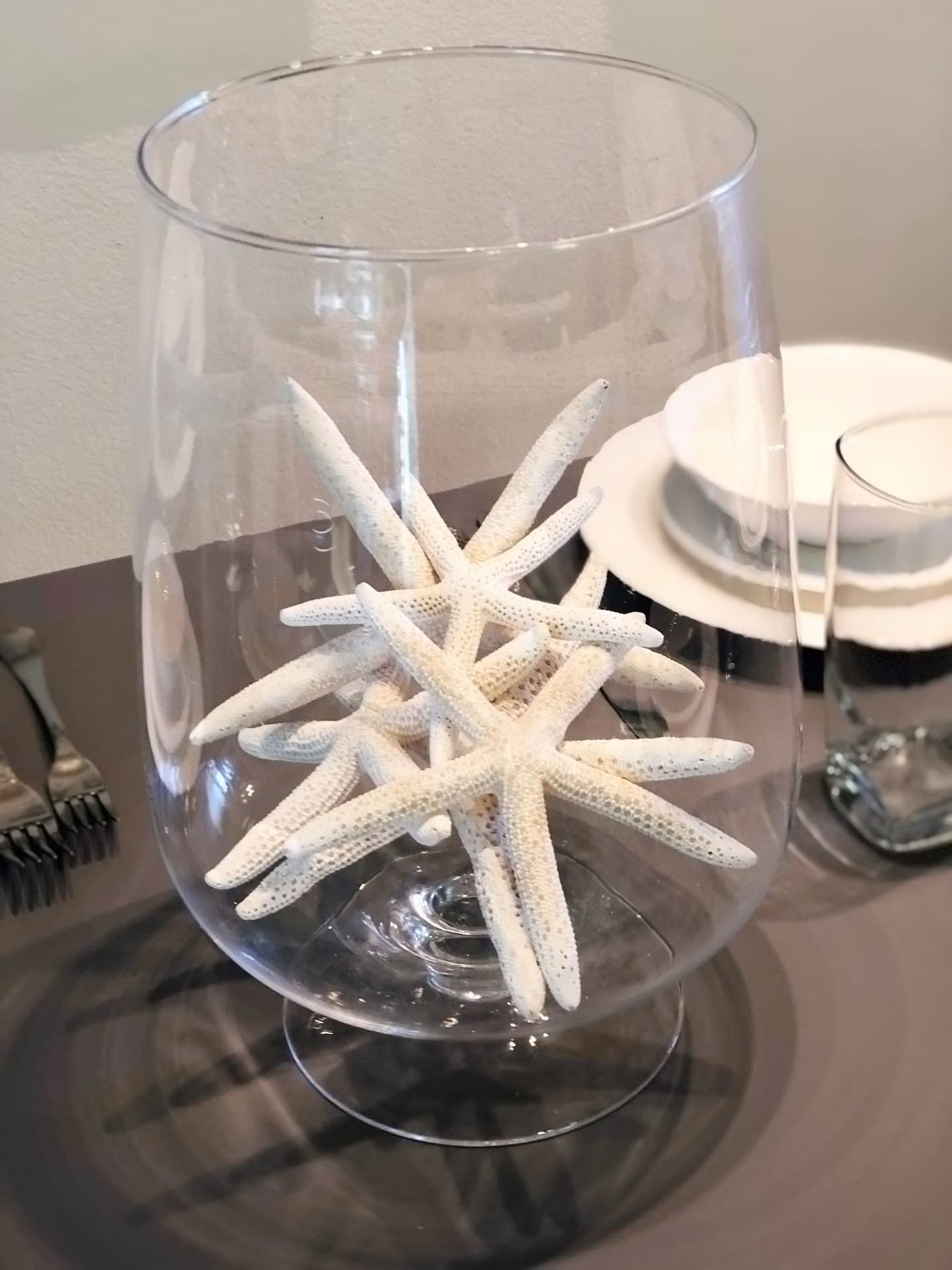 A clear glass vase with a crocheted starfish decoration.