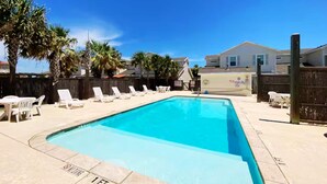 Une piscine rectangulaire dont la profondeur est indiquée par un repère à 30 cm, entourée de chaises longues et d’une clôture en bois.