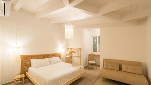 A bedroom with a wooden bed, a sofa, a chair, a desk, and a hanging light fixture. - Just Relax Home (Sant'Angelo Romano)