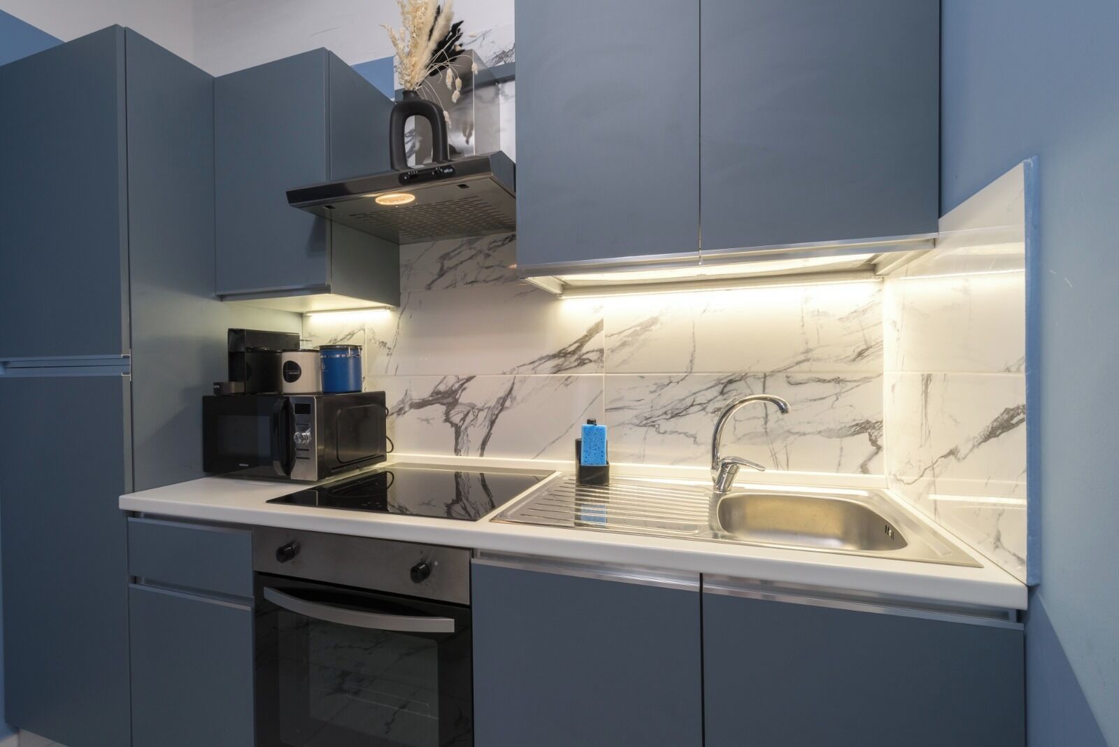 Una cocina moderna con horno integrado, microondas y pileta de acero inoxidable.