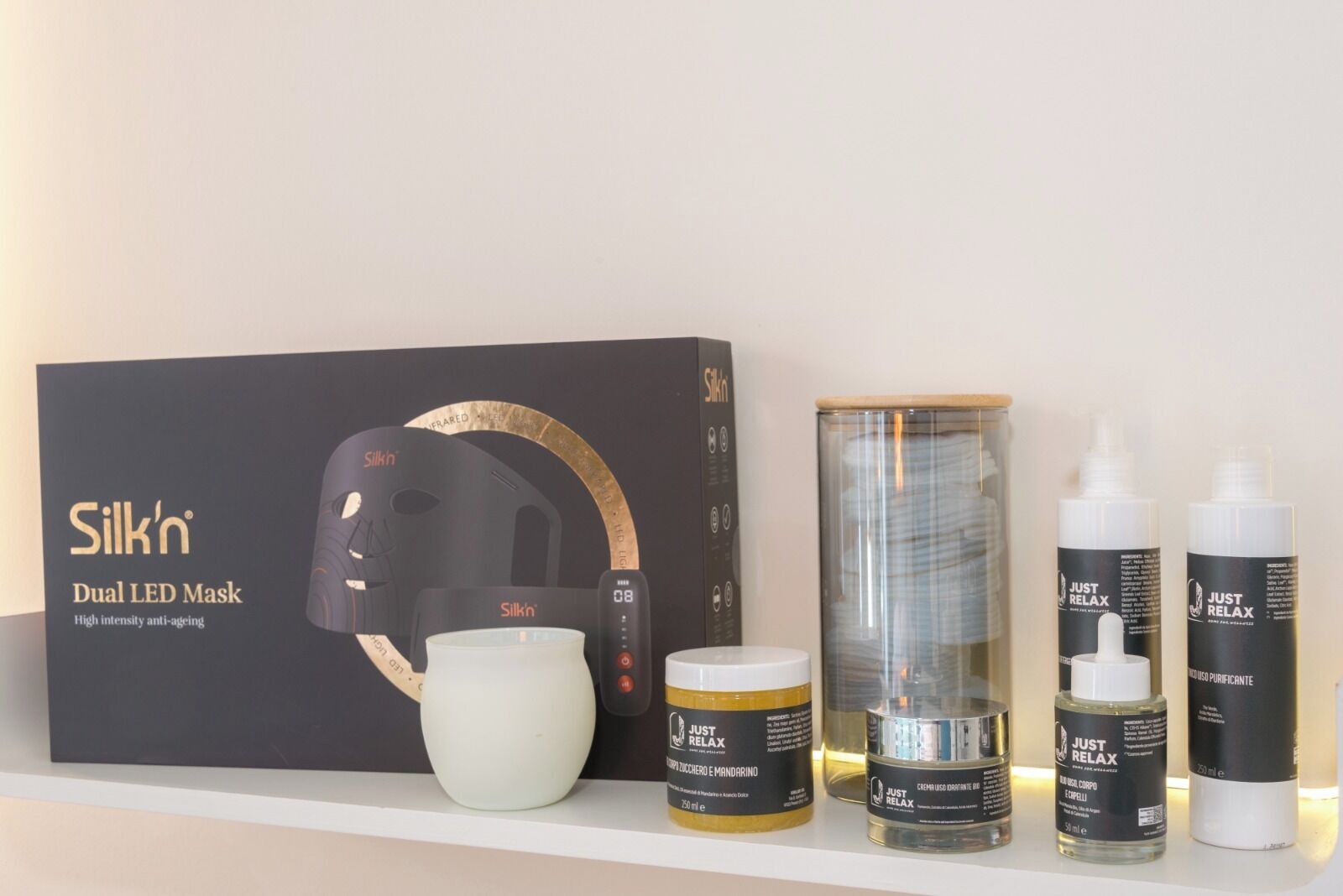 A skincare product display with a dual LED mask, a cylindrical container, and two bottles of serum.