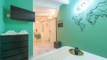 Hotelkamer met een bed, een televisie, een kunstwerk aan de muur en een badkamer zichtbaar door een geopende deur.