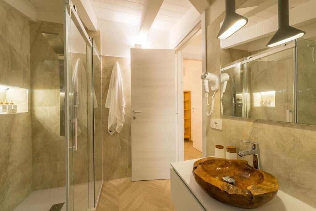 A modern bathroom with a glass shower enclosure, a wooden vanity, and a large mirror.