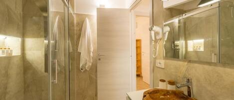 A modern bathroom with a glass shower enclosure, a wooden vanity, and a large mirror.
