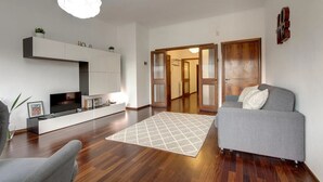 A modern living room with a grey sofa, a flat-screen TV, and a wooden floor. - Spacious Florence Apartment with Arno View Terrace Near Piazzale Michelangelo (Firenze)