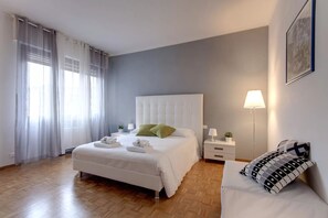 Ein Schlafzimmer mit einem Bett, Nachttischen, einer Lampe und einem Sofa.