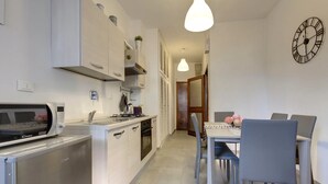 A compact kitchen with a microwave, stove, and sink. There is a dining area with a table and chairs. - Spacious Florence Apartment with Arno View Terrace Near Piazzale Michelangelo (Firenze)