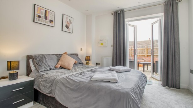Ein Schlafzimmer mit Bett, Nachttischen, Heizkörper und Blick ins Freie.