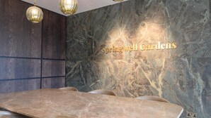 Ein stilvoller Essbereich mit einem Marmortisch, Ledersesseln und einer Wand mit dem Schriftzug 'Springwell Gardens'.