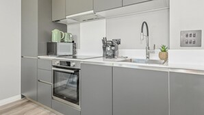 Eine moderne Küche mit grauen Schränken, einem eingebauten Backofen, einer Mikrowelle, einer Kaffeemaschine und einem Spülbecken.