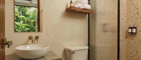 A bathroom with a white sink, toilet, and a shower area with a glass door.