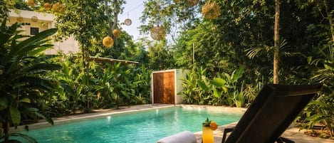 A poolside area with a lounge chair, a towel, and a drink.