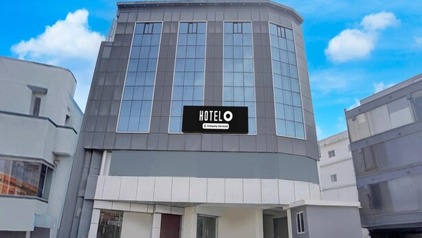En modern hotellbyggnad med en tydlig skylt som visar ordet ”HOTEL”, en böjd fasad och en trappa som leder till entrén.