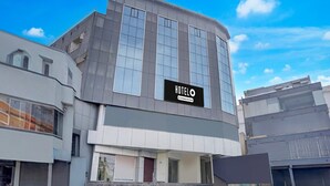 En modern hotellbyggnad med en framträdande skylt, en trappa som leder upp till entrén och en klar himmel.