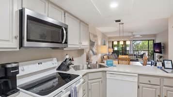 A modern kitchen with a microwave, stove, and dishwasher. There is a dining area with a table and chairs.