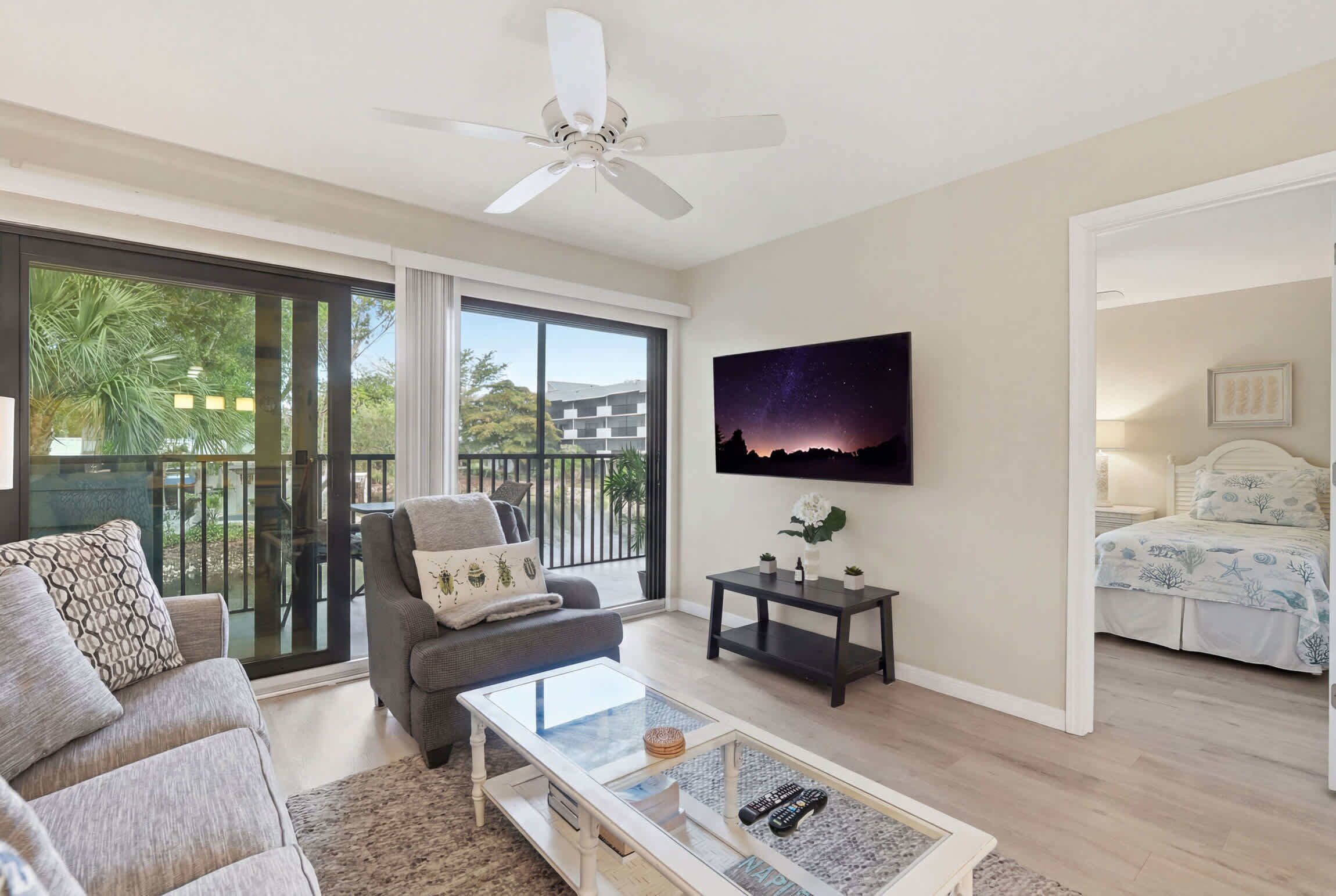 A modern living room with a sofa, armchair, coffee table, and a TV mounted on the wall.