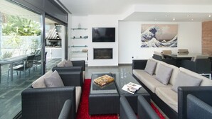 Ein modernes Wohnzimmer mit Korbmöbeln, einem Flachbildfernseher und einem großen Kunstwerk.