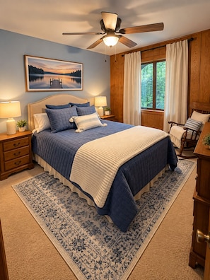 A bedroom with a bed, a nightstand, a lamp, a ceiling fan, a window with curtains, and a wooden headboard. - Great Escape at Lake Harmony • 4BR • Beach Access • Game Room • Fire Pit (Lake Harmony)