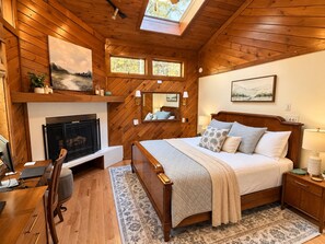 A bedroom with a wooden ceiling, a fireplace, a bed with pillows, a desk with a chair, and a window. - Great Escape at Lake Harmony • 4BR • Beach Access • Game Room • Fire Pit (Lake Harmony)