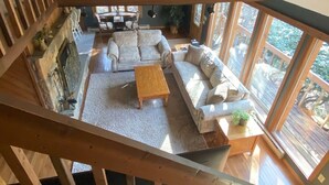 A spacious living area with a high ceiling, wooden beams, a fireplace, a sofa set, a coffee table, and large windows. - Lake Harmony Luxury Escape,  Lake Access, Near Big Boulder, Sleeps 12 (Lake Harmony)