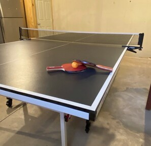 A ping pong table with a paddle and ball in the center. - Great Escape at Lake Harmony • 4BR • Beach Access • Game Room • Fire Pit (Lake Harmony)
