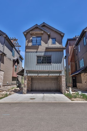 A two-story residential building with a garage, stone foundation, and a clear blue sky. - Brand New! I Downtown Winter Park w/Hot Tub (Winter Park)