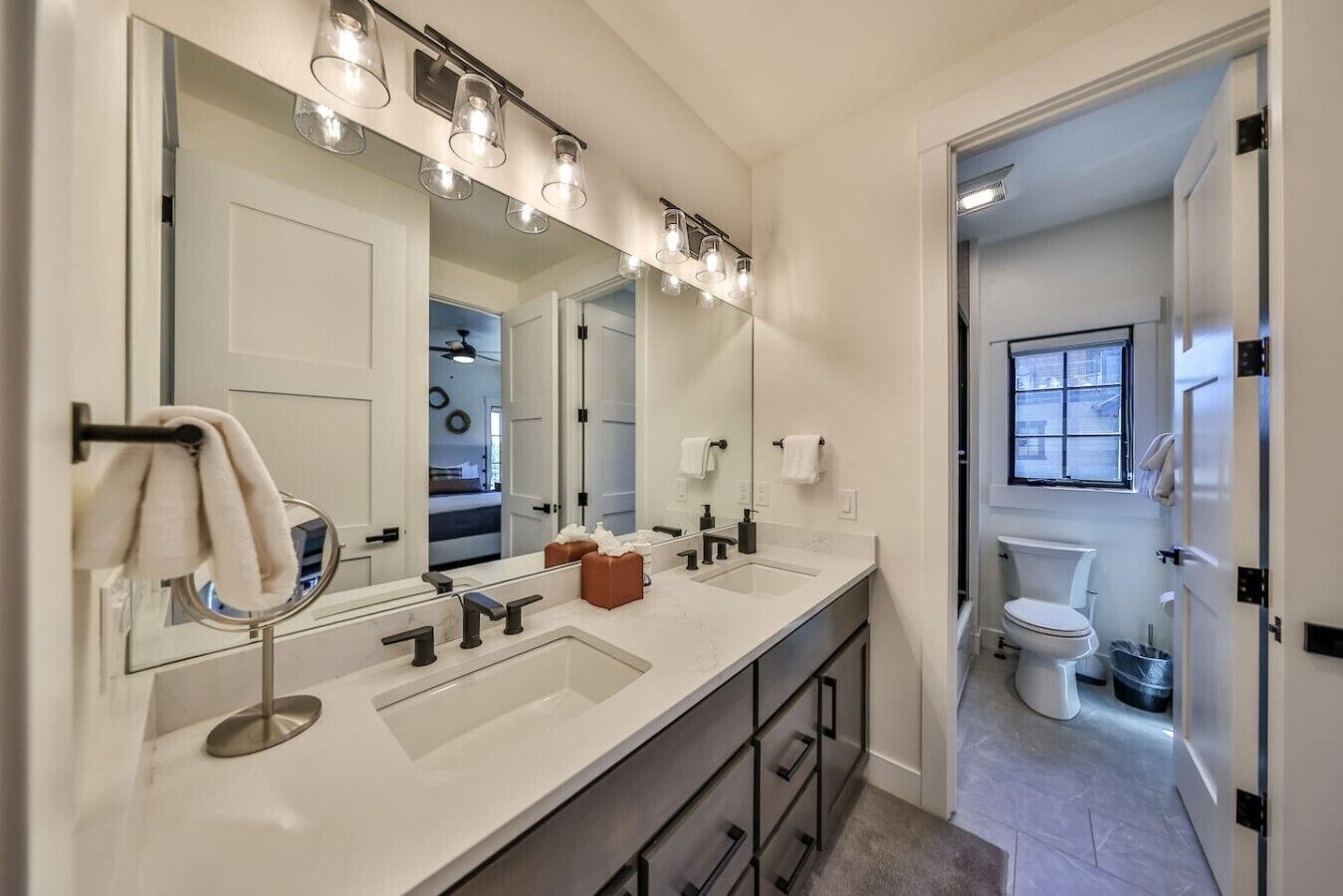Un bagno moderno con uno specchio grande, due lavabi e un water.
