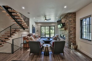A modern interior with a staircase, a dining area with chairs and a table, and a large window. - Brand New! I Downtown Winter Park w/Hot Tub (Winter Park)