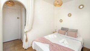Ein Schlafzimmer mit Bett, Kissen, Nachttisch, Lampe und Spiegel an der Wand.