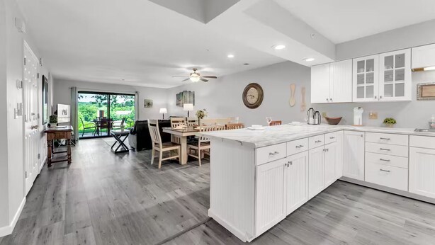 Une cuisine moderne avec des meubles blancs, un grand îlot central et un coin repas doté de chaises en bois.