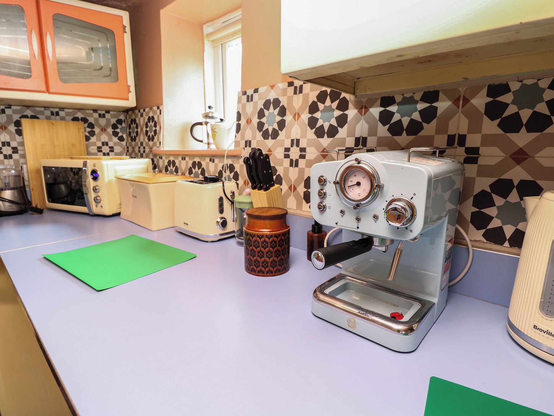 Une cuisine équipée d’une machine à café, d’un grille-pain et d’un crédence décorée.