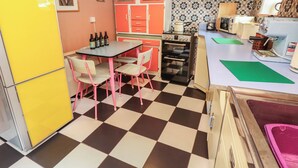 A compact kitchen with a checkered floor, a table with chairs, a refrigerator, and a microwave. - Dairy Cottage (Ventnor)