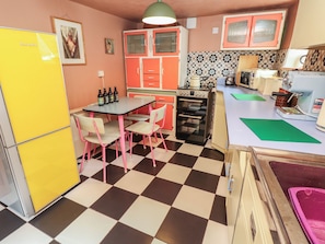 A compact kitchen with a checkered floor, a table with chairs, a refrigerator, and a microwave. - Dairy Cottage (Ventnor)