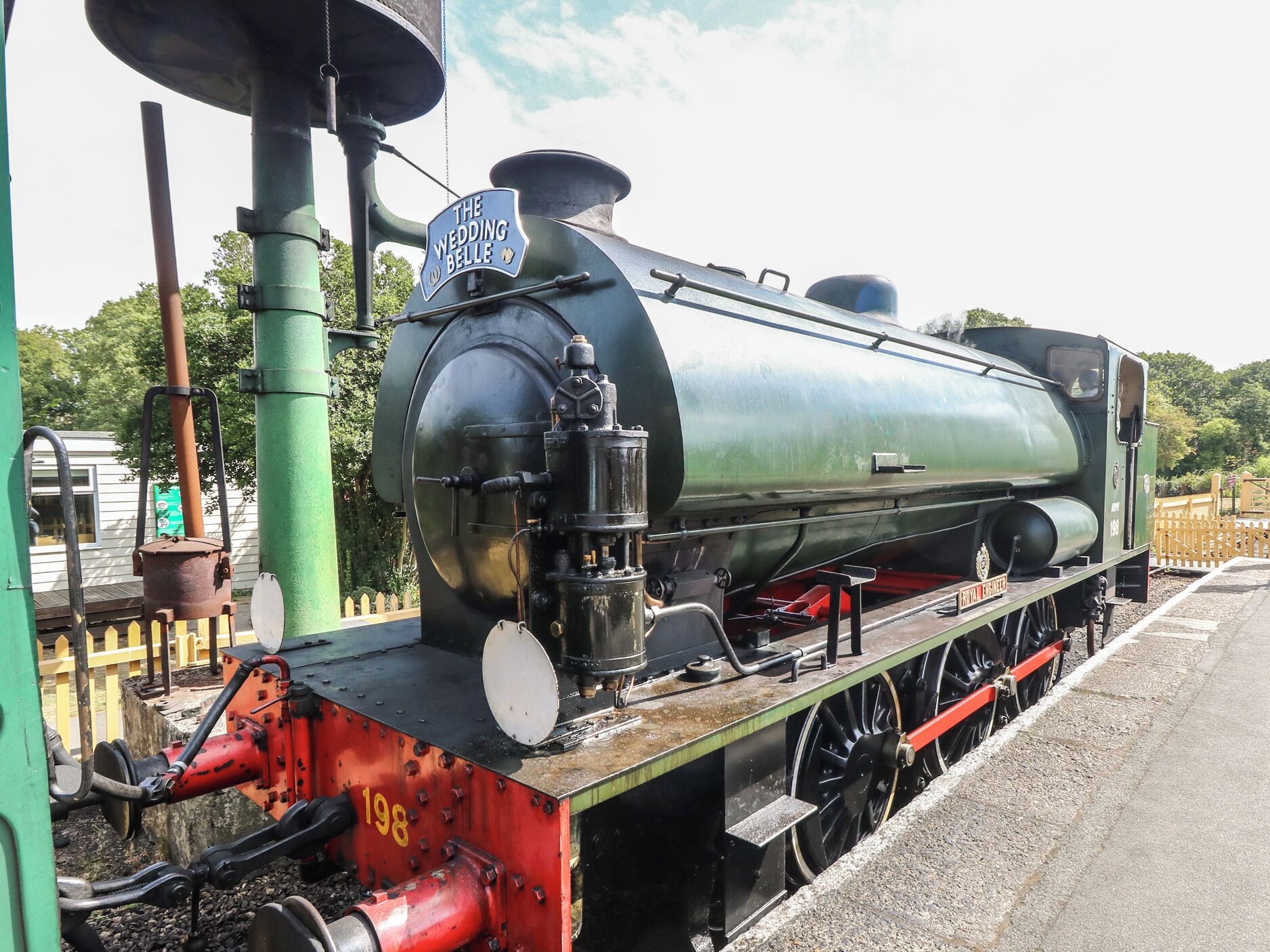 A vintage steam locomotive with a sign reading 'The Wedding Belle' parked on tracks.