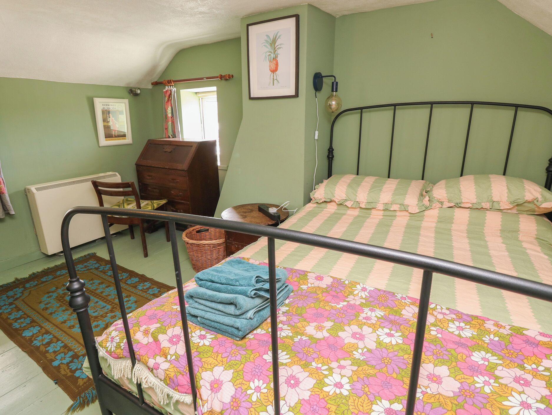 A bedroom with a bed, a chair, a dresser, and a radiator.