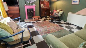 A living room with a checkered floor, a fireplace, a television, and a framed picture on the wall. - Dairy Cottage (Ventnor)