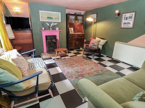 A living room with a checkered floor, a fireplace, a television, and a framed picture on the wall. - Dairy Cottage (Ventnor)