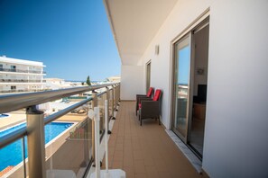 A balcony with a pool, chairs, and a view of the sea. - Albufeira 2-Bedroom Apartment w/ Pool, Sauna & Gym (Albufeira)