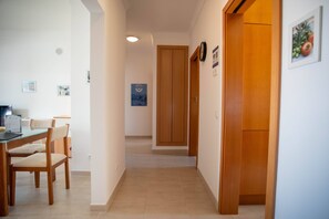 A hallway with a dining area, a wooden door, and a wall-mounted clock. - Albufeira 2-Bedroom Apartment w/ Pool, Sauna & Gym (Albufeira)